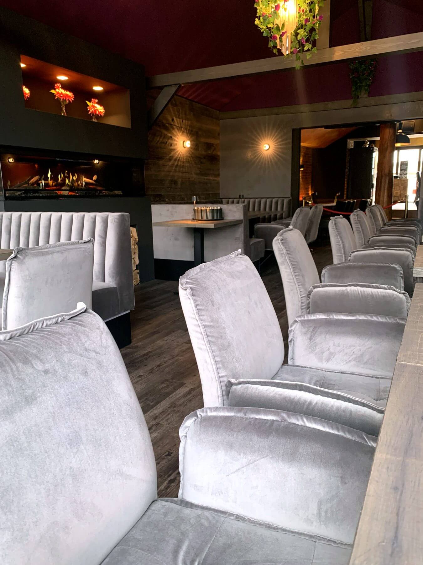 Lounge mit Polstersesseln und Kaminambiente Lounge im Die2 Neubiberg mit hellen Polstersesseln, Kaminambiente und dunklen Wandakzenten