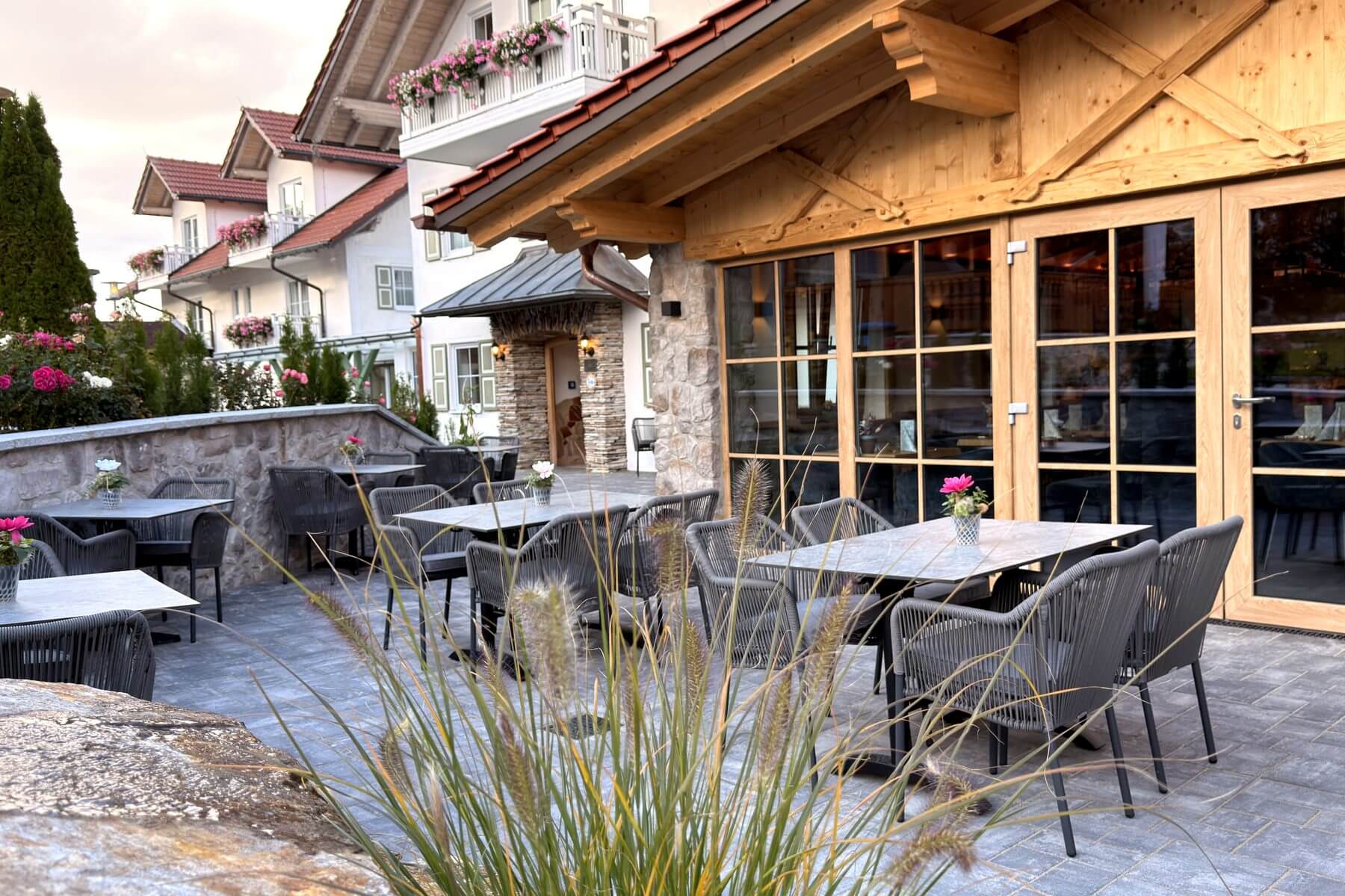 Terrassenbereich mit Gartenblick Terrassenbereich des Restaurant Pfeiffer am Wörthsee mit grauen Stühlen, Tischen und Blick zum Gebäude