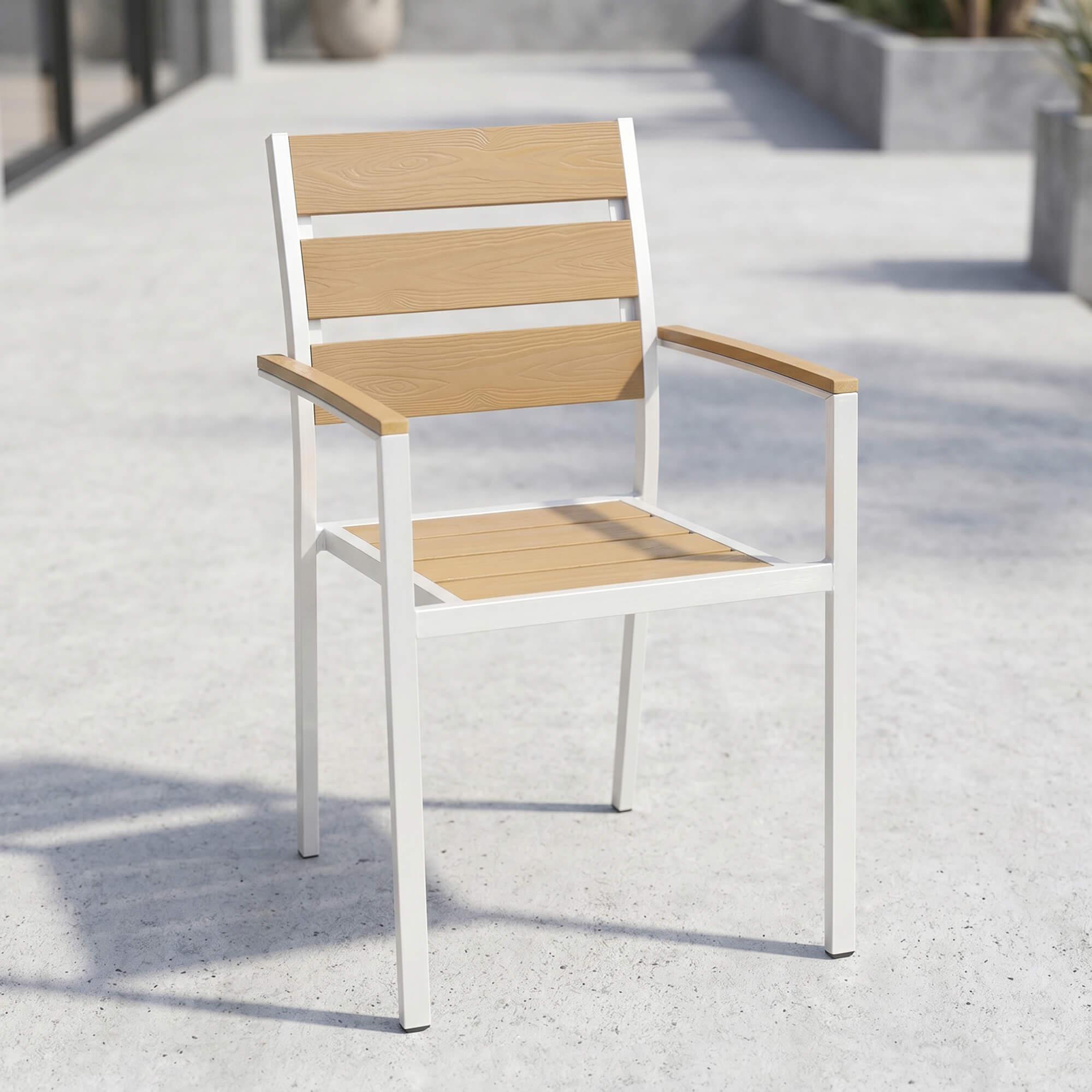 Stapelbarer Outdoorstuhl in Teak für Gastronomie-Terrassen Stapelbarer Outdoorstuhl in Teak mit Armlehnen auf gepflasterter Terrasse