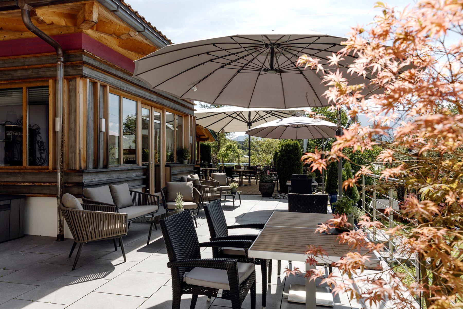 Terrassenbereich mit Loungeset und Schirm Terrassenbereich im Landhotel zum Bad in Krün mit Raminota Lounge Set, Sonnenschirm und Tischen