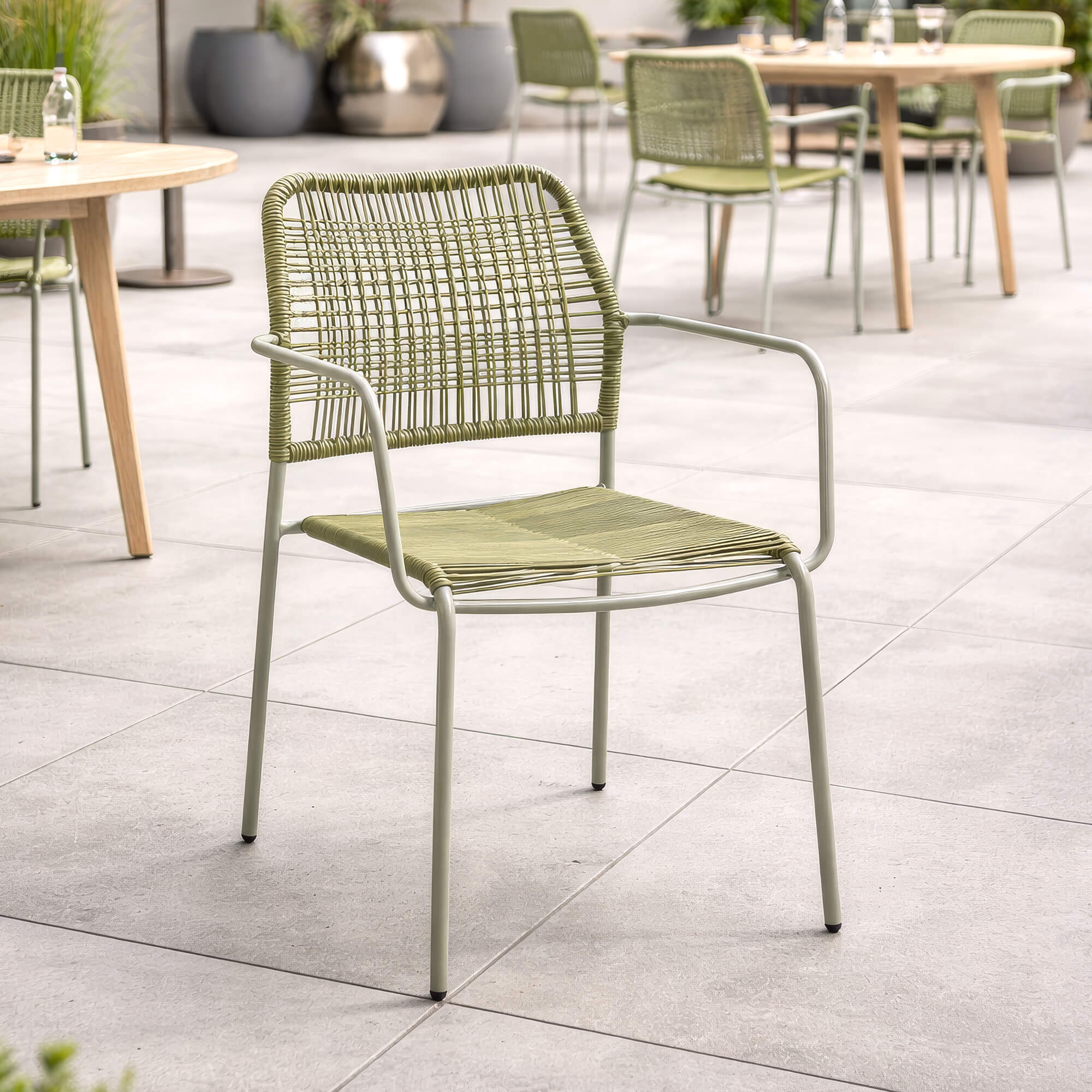 Armlehnenstuhl Cordone – grüner Outdoor-Armlehnenstuhl aus Rope-Geflecht auf sonniger Terrasse an einer Poolbar