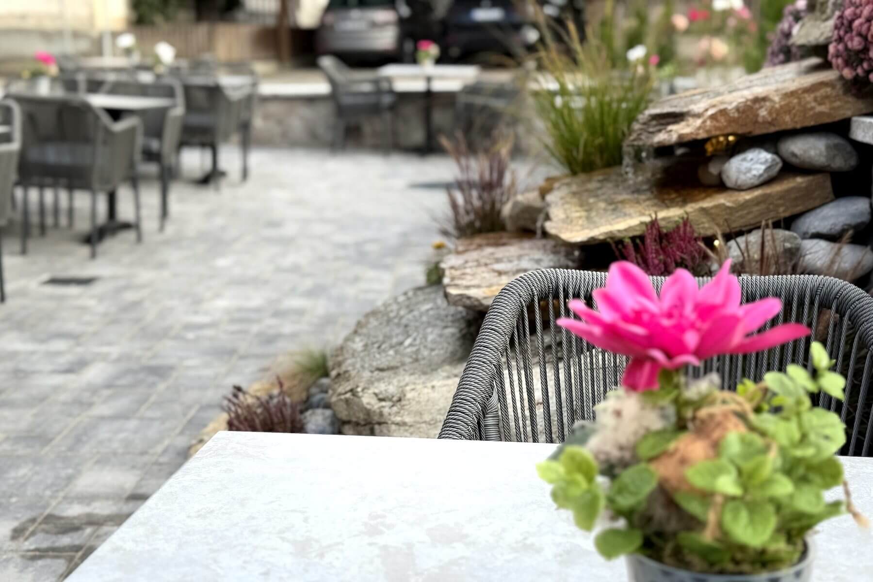Terrassendetail im Restaurant Pfeiffer am Wörthsee Detailaufnahme der Terrasse im Restaurant Pfeiffer am Wörthsee mit Tisch, Pflanze und grauen Outdoor-Stühlen