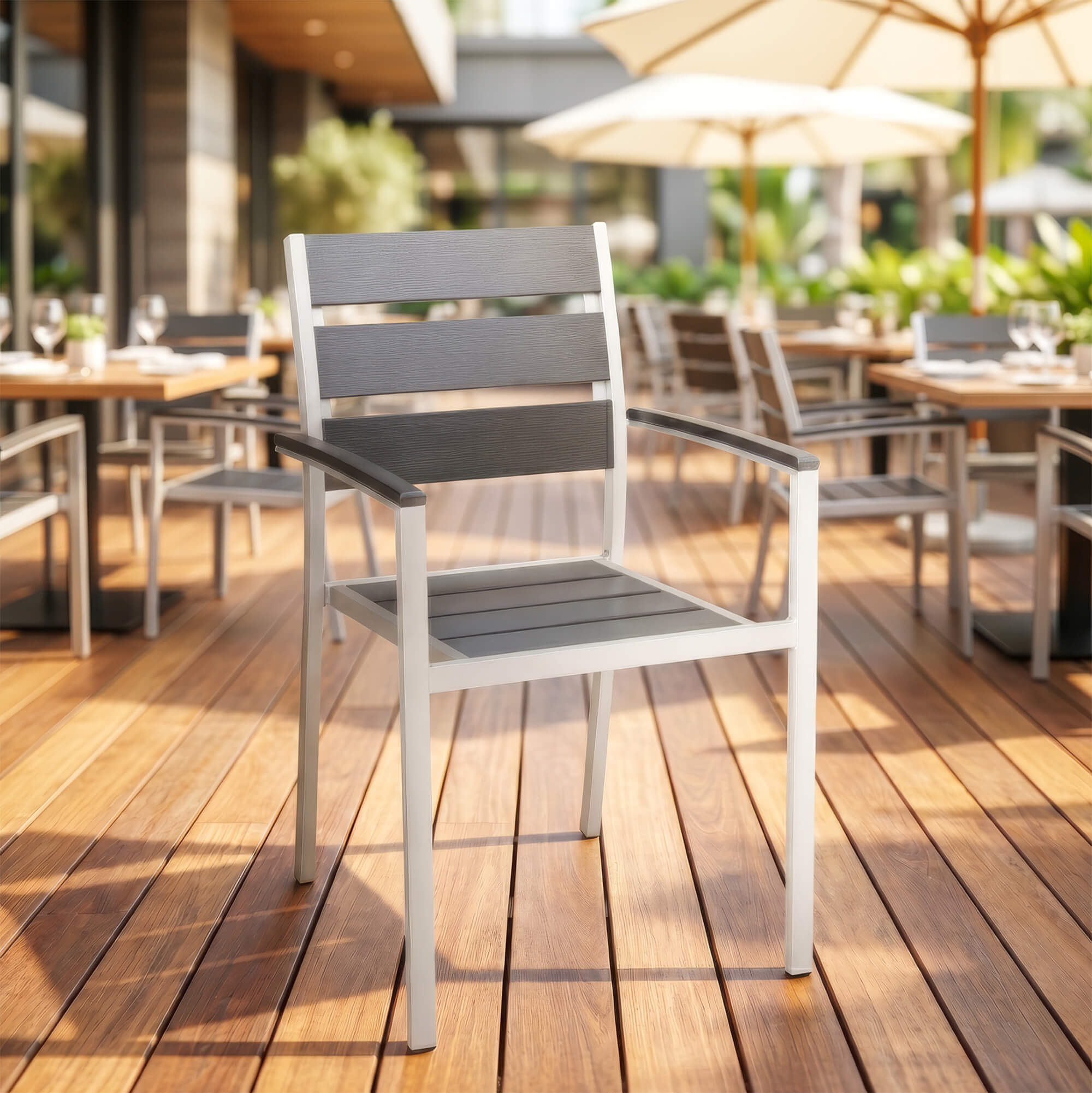 Stapelbarer Outdoorstuhl in Grau mit Armlehnen auf Restaurant-Terrasse
