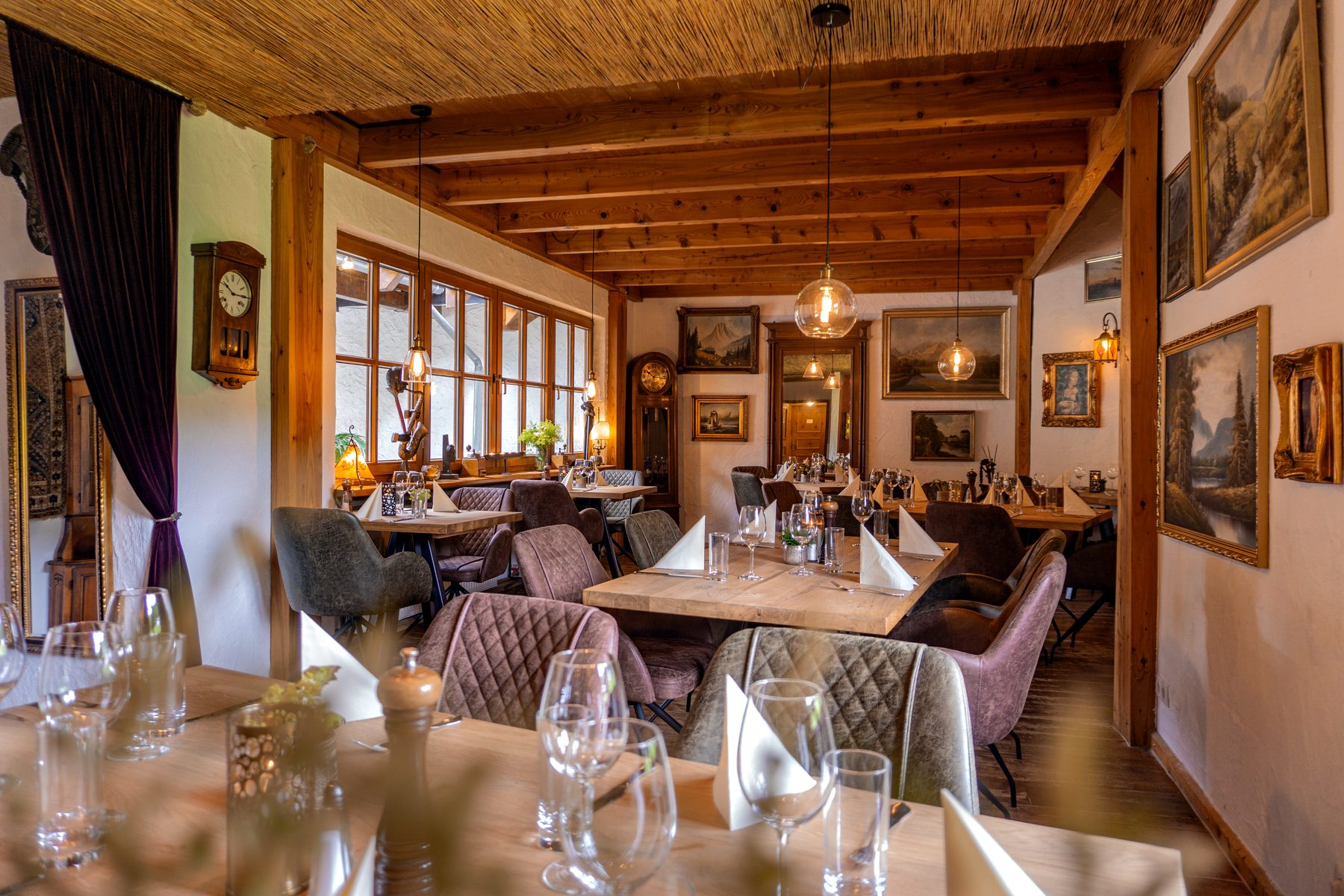 Tischgruppen im Alten Wohnzimmer der Eifeler Seehütte mit FANO-Stühlen, Holztischen und Bildern an der Wand