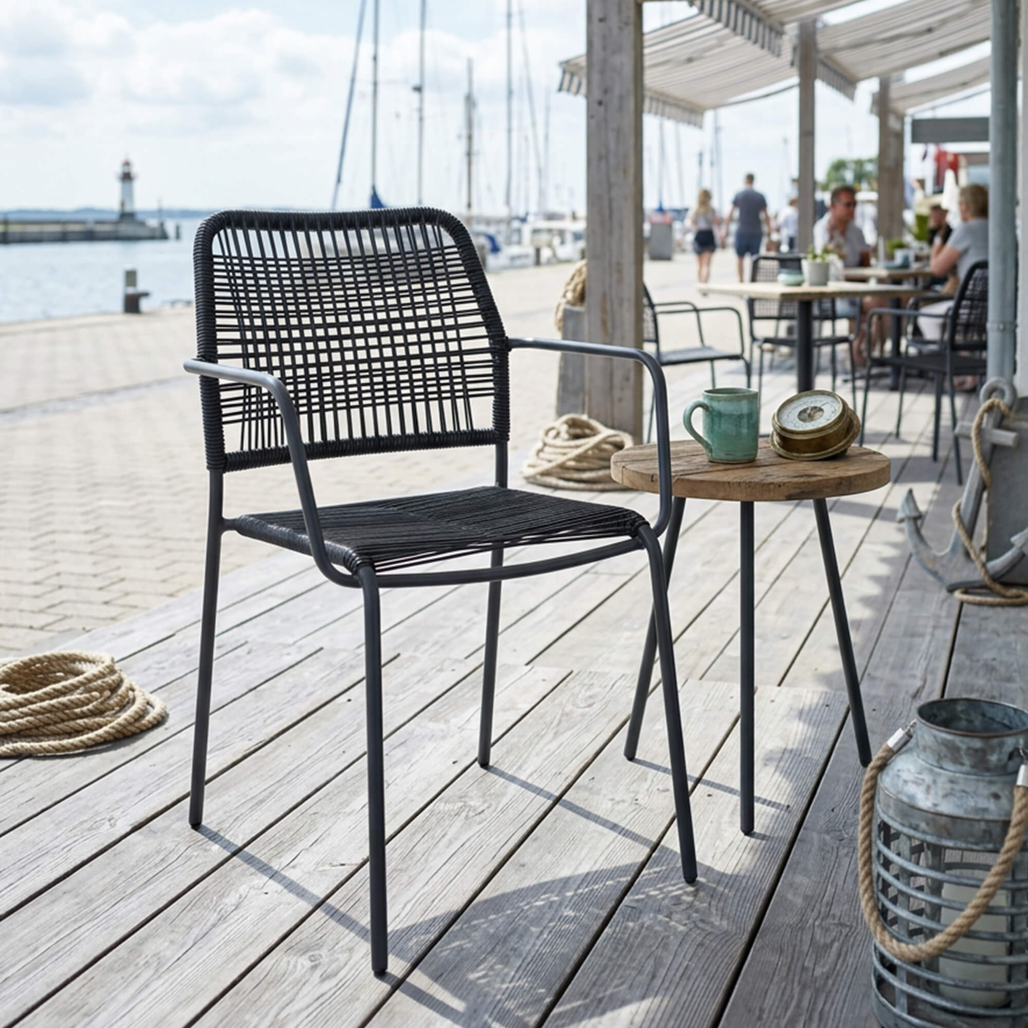 Outdoorstuhl Cordone – anthrazitfarbener Outdoorstuhl mit Rope-Geflecht auf Holzdeck am Wasser