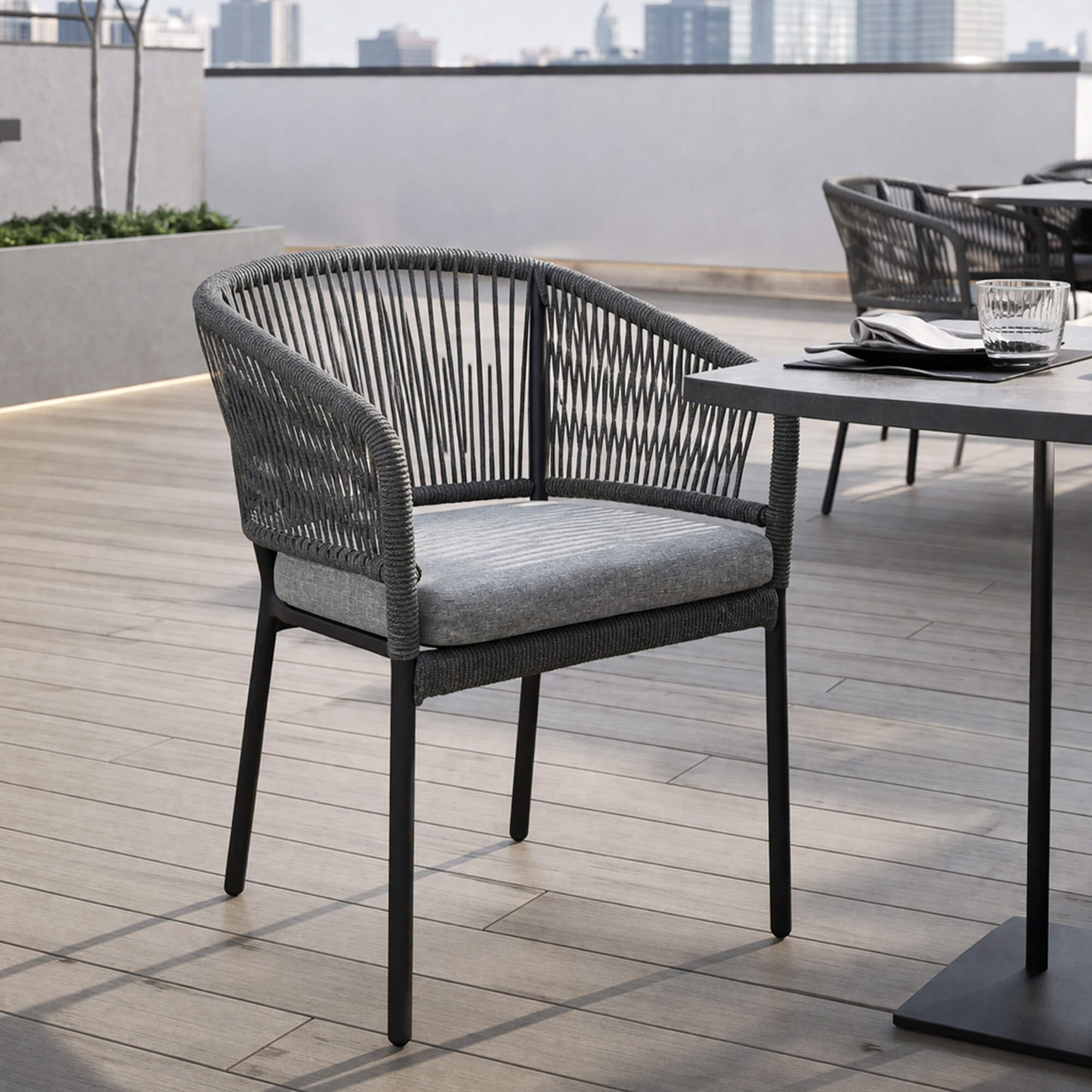 Outdoorstuhl Densa – schwarzer Outdoorstuhl mit Polsterkissen auf moderner Terrasse am Wasser