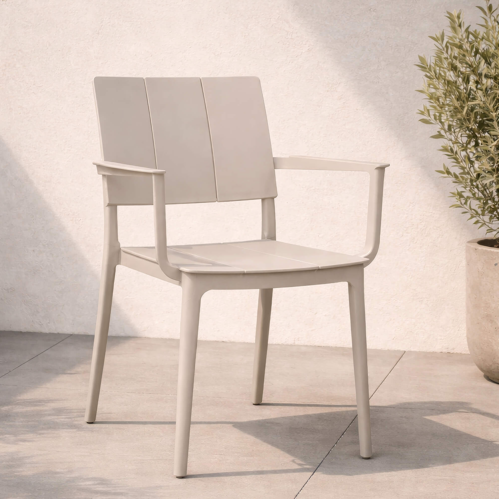 Outdoor Kunststoffstuhl Foma Light Grey mit Armlehnen Outdoor Kunststoffstuhl Foma in Light Grey mit Armlehnen auf heller Terrasse vor strukturierter Wand