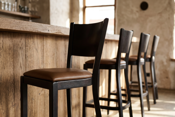 Holzbarhocker mit schwarzem Sitz an Theke