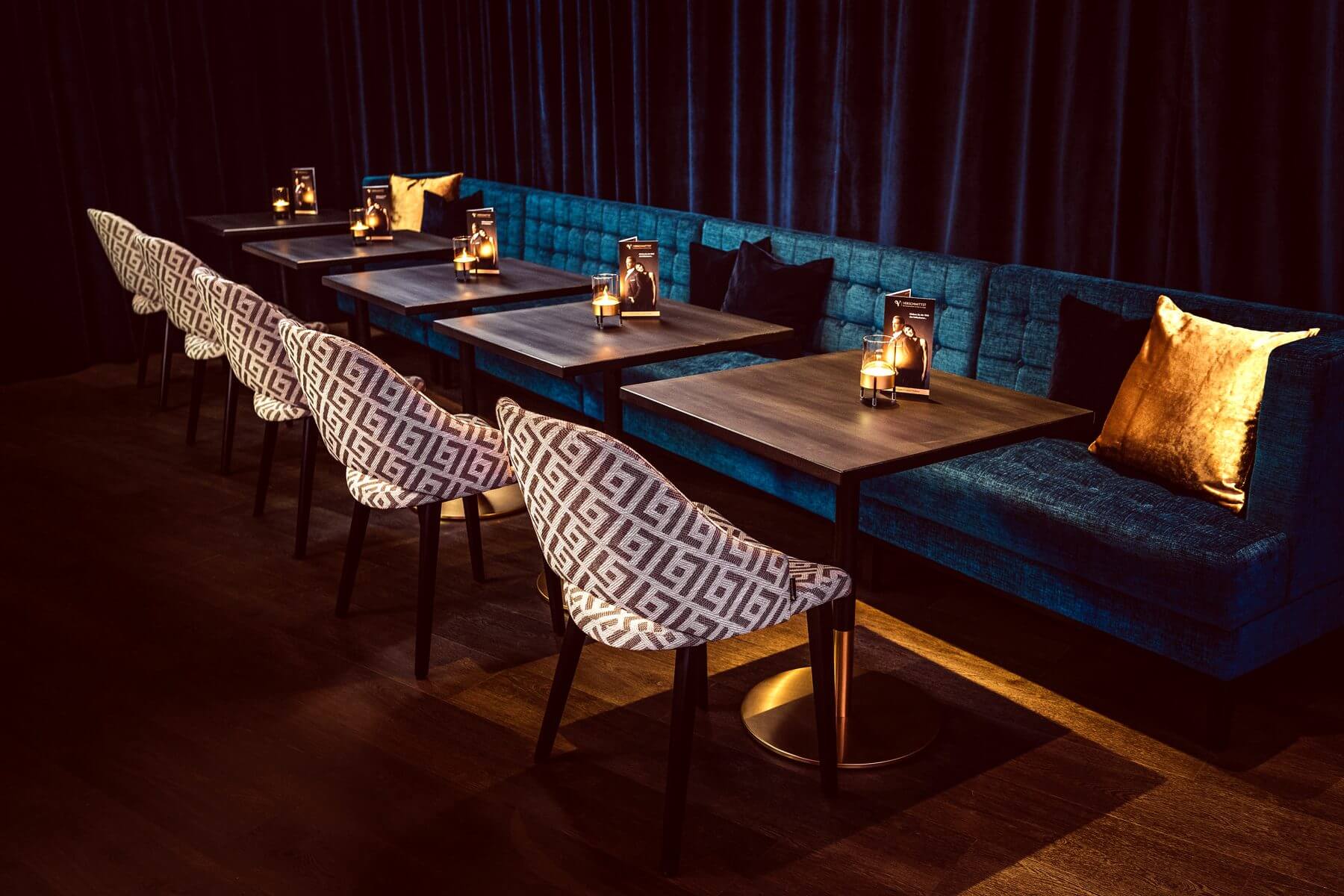 Cizron-Stühle an langer Sitzreihe Lange Sitzreihe in der Bar & Lounge von VERSCHMITTST mit gemusterten Cizron-Stühlen und blauer Polsterbank
