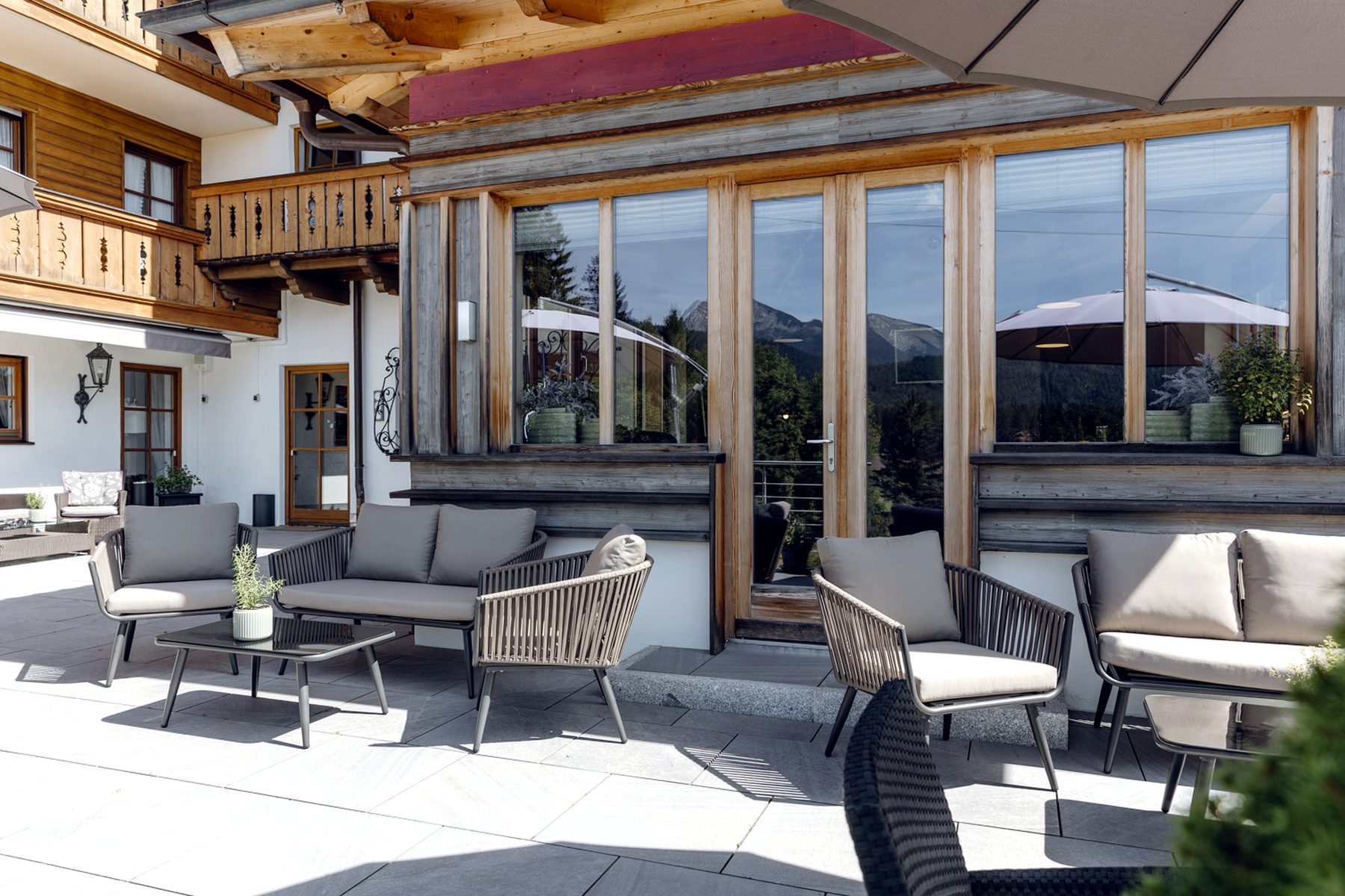 Loungebereich am Restaurant Loungebereich vor dem Esszimmer am Bichl mit Outdoor-Möbeln und großen Fenstern