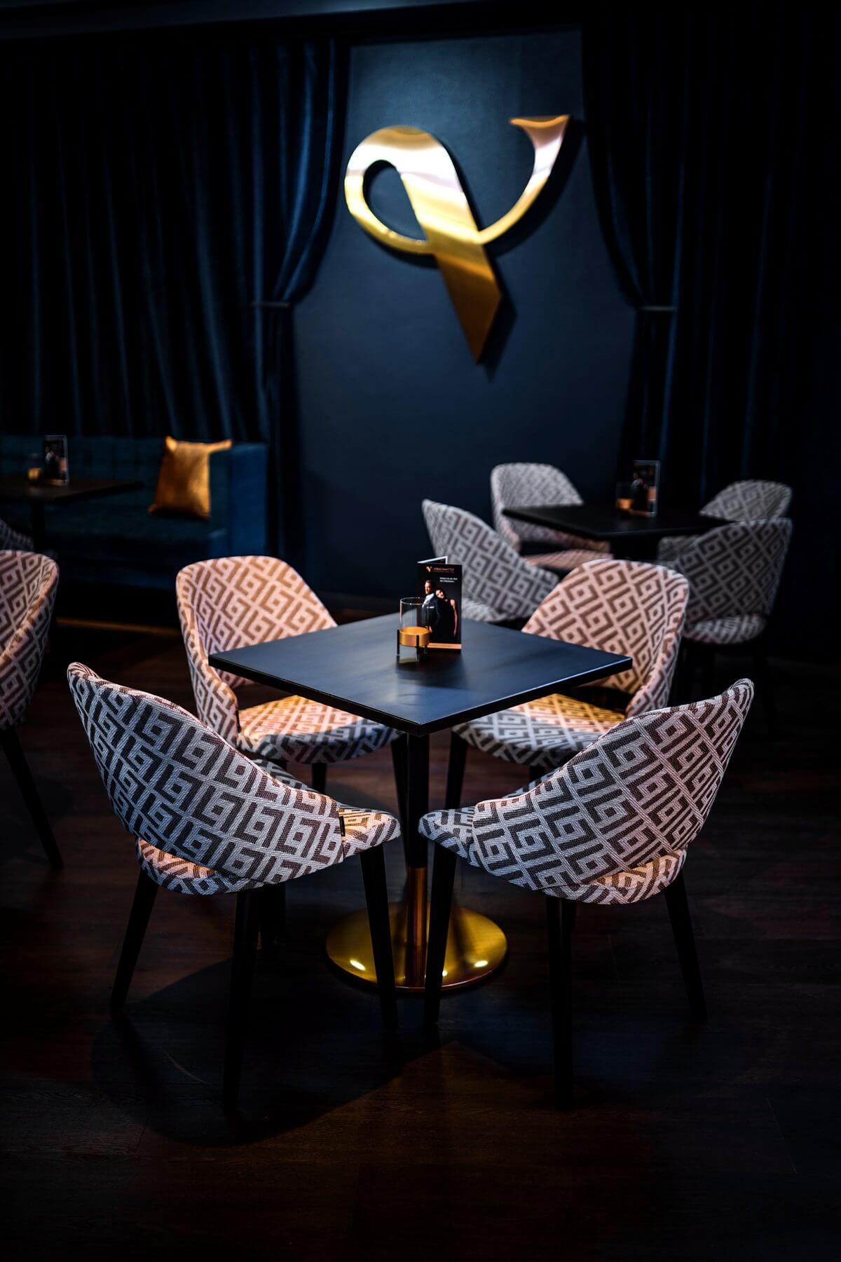 Sitzgruppe im Hochformat Hochformat einer Sitzgruppe in der Bar & Lounge von VERSCHMITTST mit Cizron-Stühlen und dunklem Wandvorhang