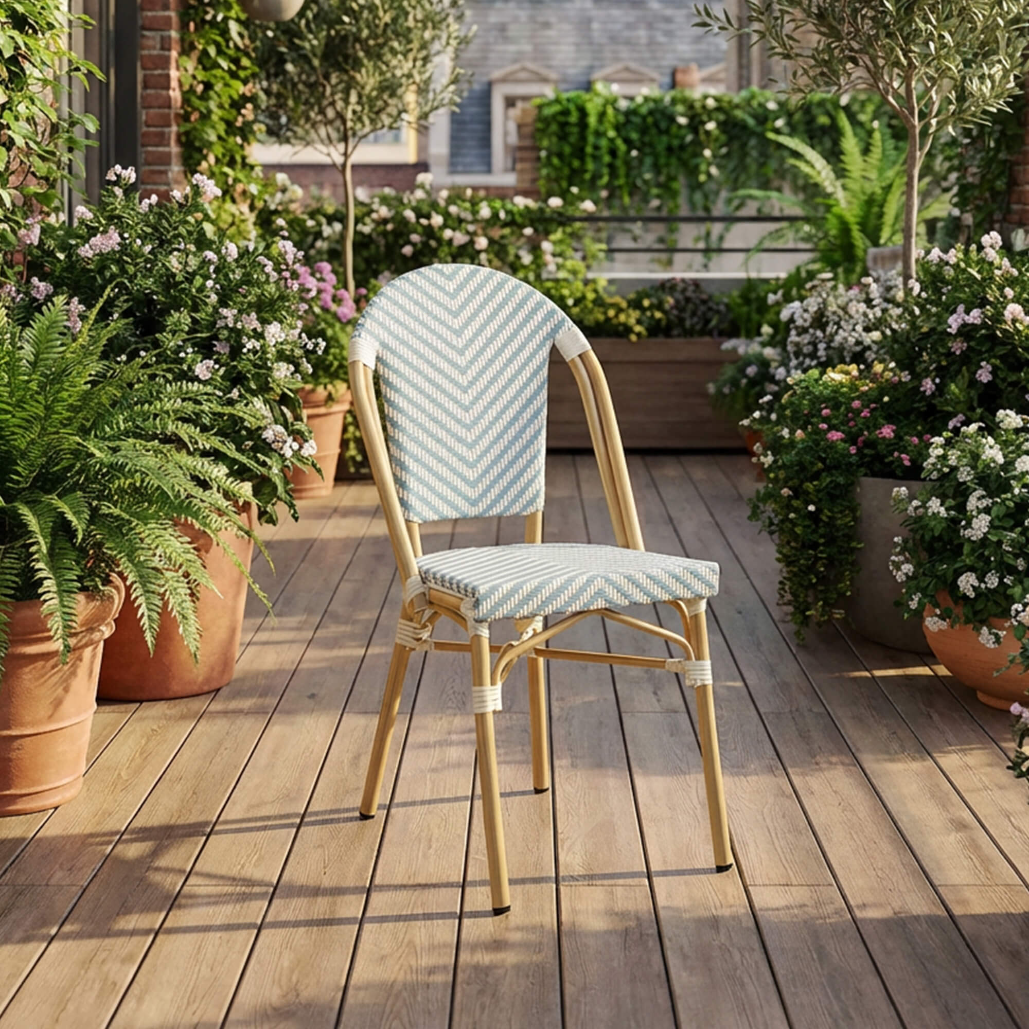 Outdoorstuhl Zypern – blau-weißer Bistrostuhl in Flechtoptik auf stilvoller Holzterrasse mit Blumen