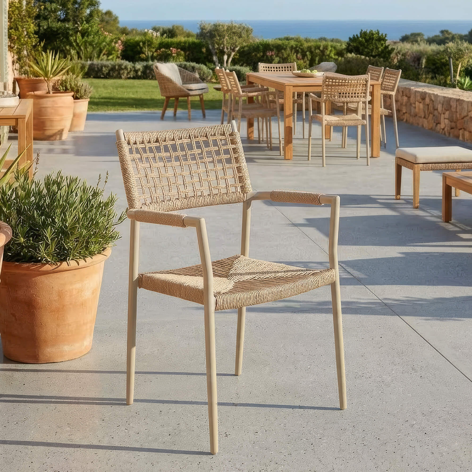 Outdoorstuhl Armlehnenstuhl Sisson Cream für moderne Gastro-Terrassen Outdoorstuhl Armlehnenstuhl Sisson Cream mit geflochtener Sitz- und Rückenfläche auf heller Außenterrasse