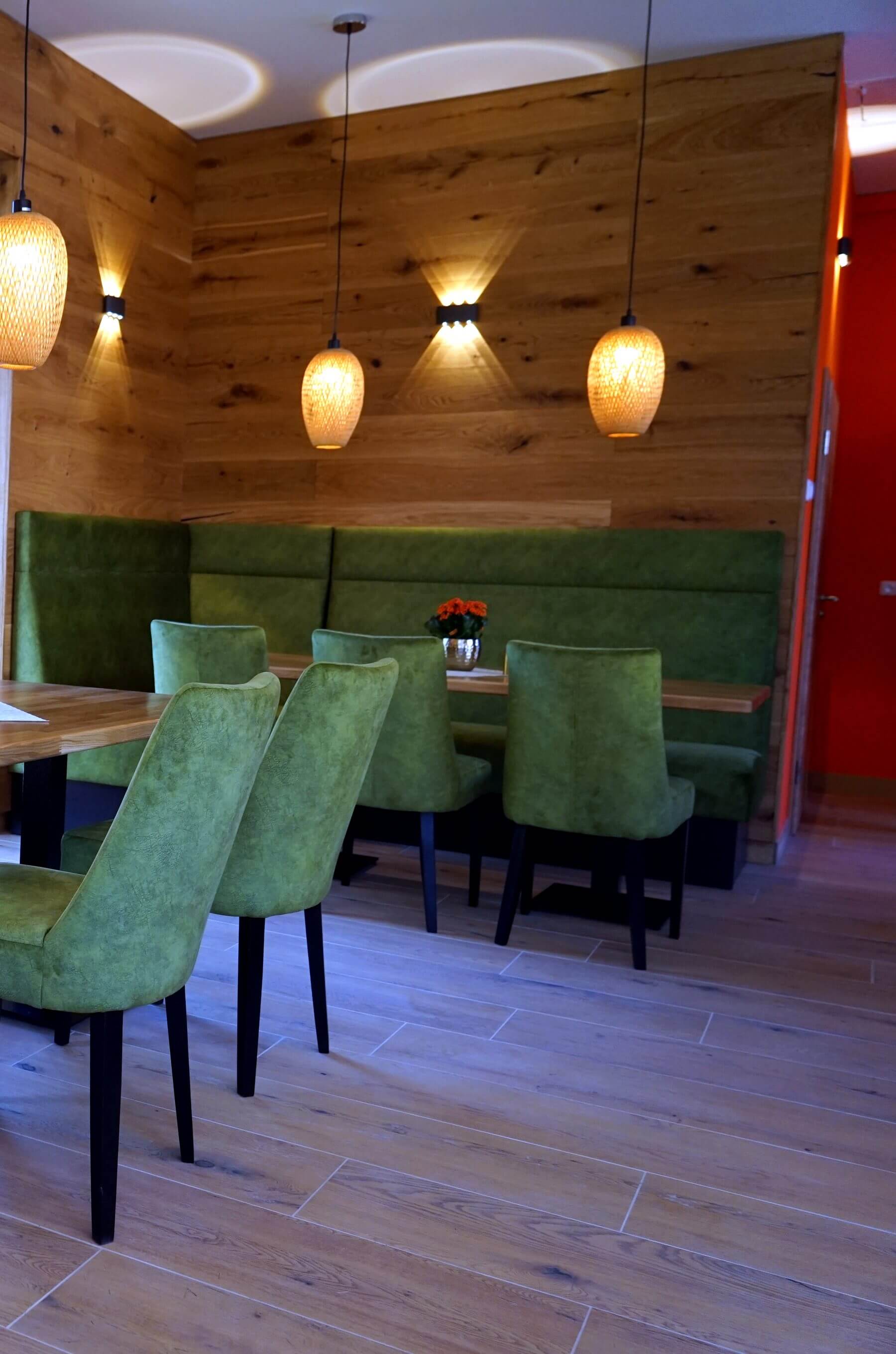 Sitzgruppe mit Holzwand und Pendelleuchten Sitzgruppe im Cafe Flow mit Holzwand, Pendelleuchten, Polsterbank und Gastronomiestuehlen