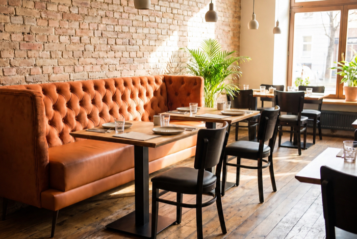 Gepolsterte Restaurantbank mit Tischen und Stühlen