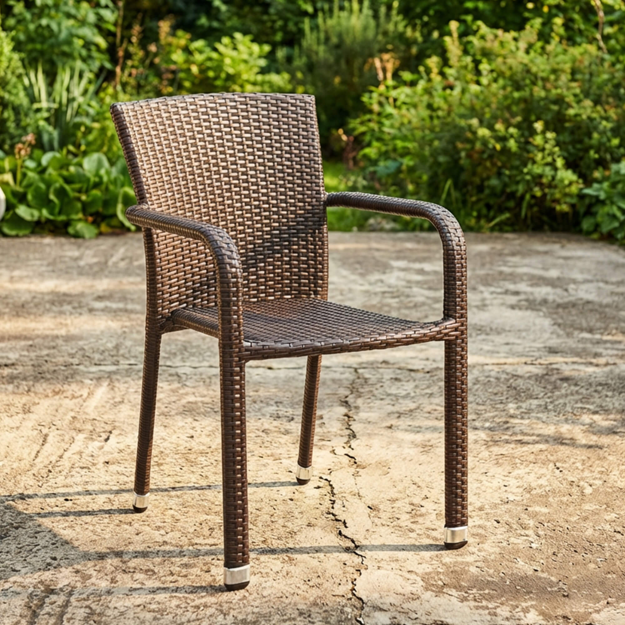 Outdoorstuhl Basato – brauner Outdoorstuhl aus Geflecht mit Armlehnen auf Terrasse im Grünen